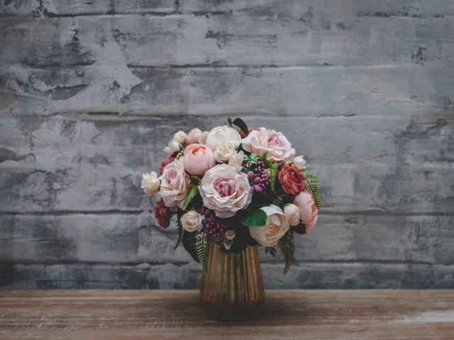 Розовый букет роз  стоит у серой стены 