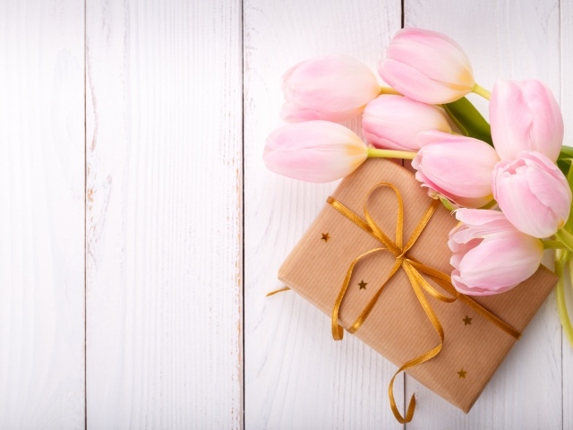 Букет нежных тюльпанов с подарком на деревянном столе
