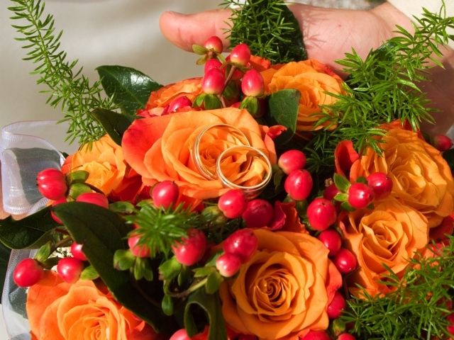 Букет оранжевых роз с красными ягодами и обручальными кольцами
