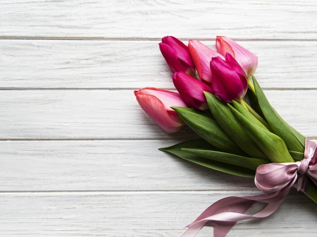 Весенний букет розовых тюльпанов с бантом на столе