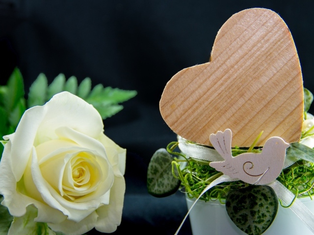 Деревянное сердце и белая роза на столе 