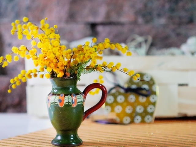 Желтые цветы мимозы в маленькой вазе на столе