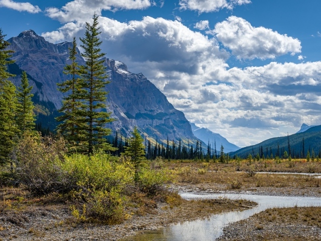 Красивый горный пейзаж под густыми белыми облаками в голубом небе