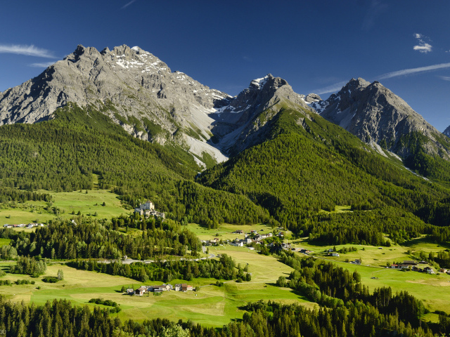 Высокие швейцарские Альпы покрыты зеленью под голубым небом 