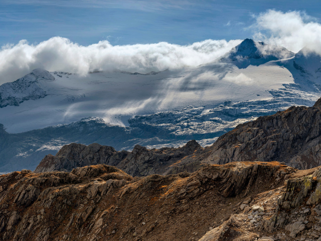 Густые белые облака над заснеженными Альпами
