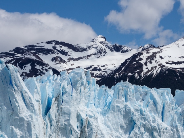 Голубой ледник на фоне заснеженных гор 