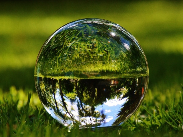 Стеклянный шар  водой на зеленой траве