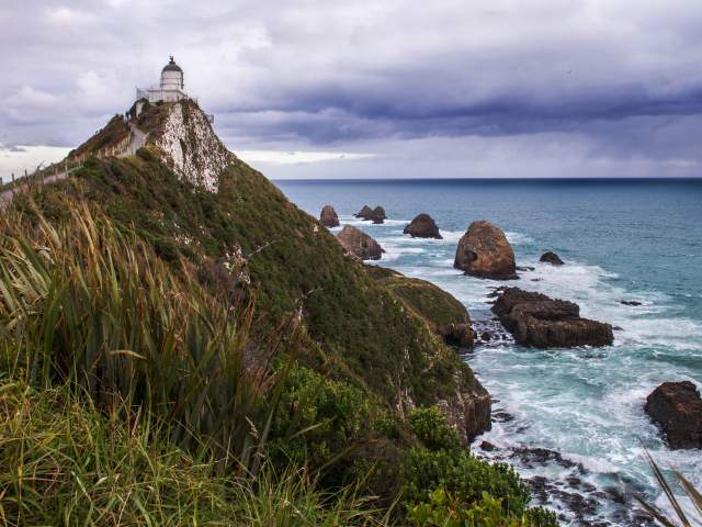 Маяк на вершине утеса у моря под грозовым небом