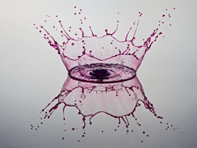 Брызги фиолетовой краски на сером фоне 