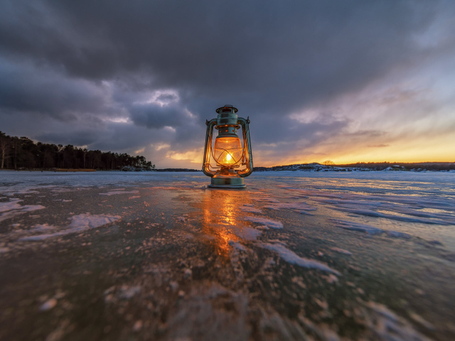 Керосиновая лампа стоит на покрытом льдом берегу