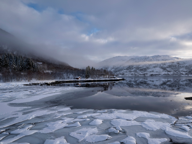 Покрытое льдом холодное озеро у гор в тумане