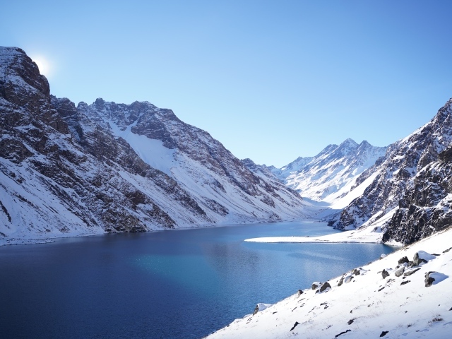 Озеро у покрытых снегом гор под голубым небом