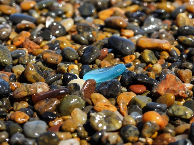 Гладкие разноцветные мелкие камни на пляже 