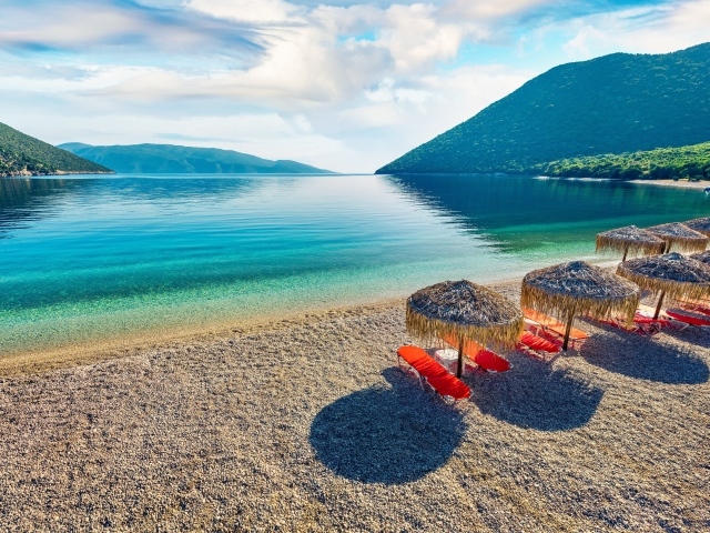 Шезлонги стоят на берегу озера у гор 