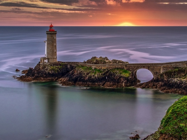 Вид на спокойное море и маяк на закате солнца 