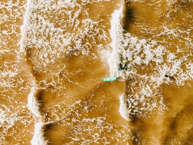 Белые волны на воде поднимают песок