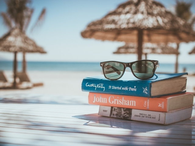 Книги и очки лежат на столе на пляже 