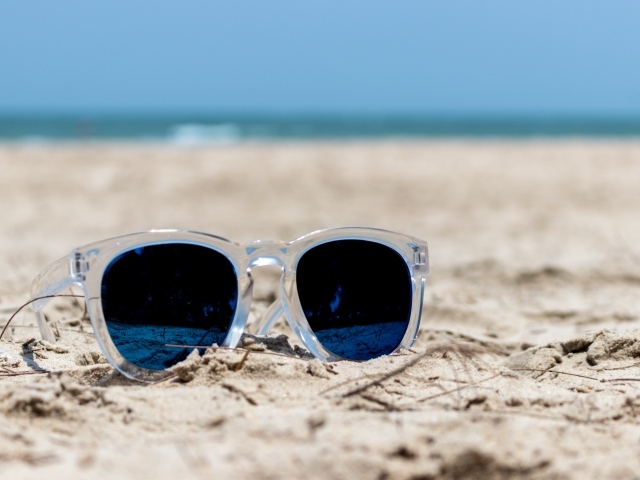Солнечные очки лежат на песке на пляже летом
