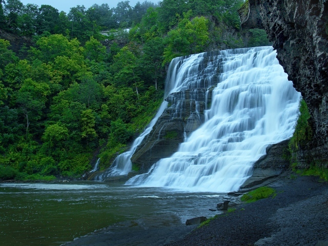 Красивый каскадный водопад с зелеными деревьями