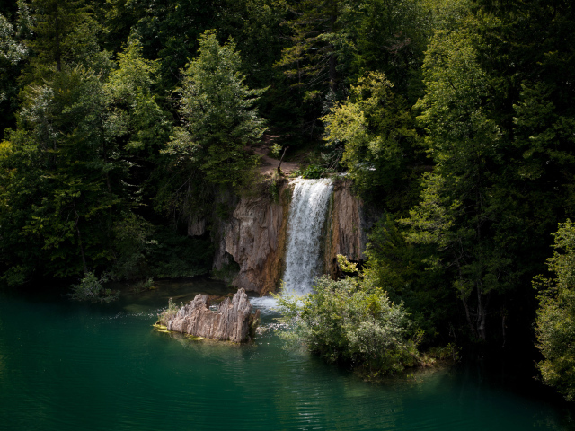 Водопад стекает со скалы в холодное озеро 