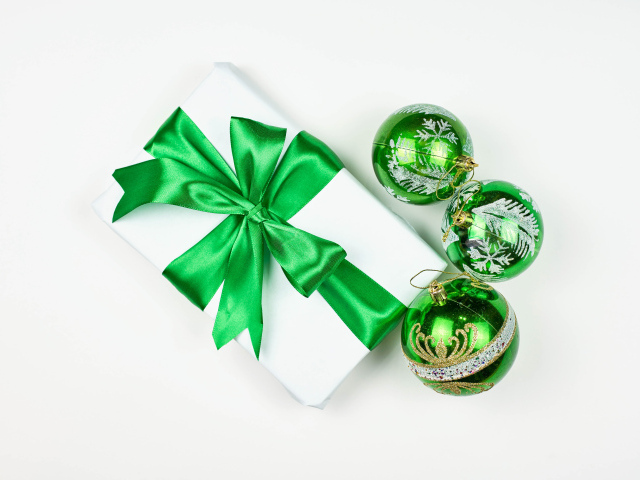 Подарок и три елочных шара на белом фоне 
