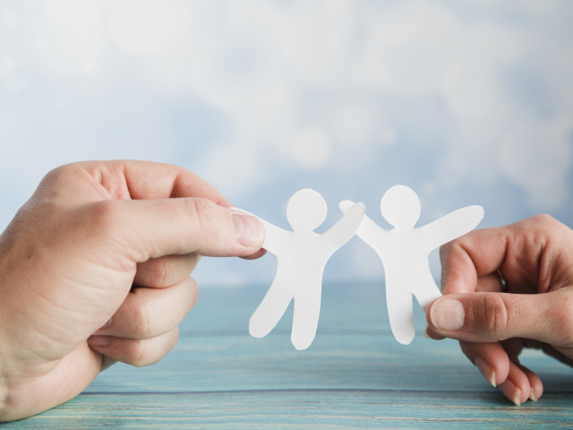 Два бумажных человечка в руках 