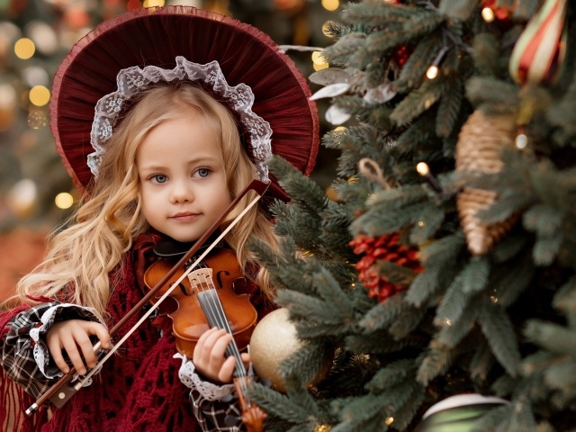 Красивая маленькая девочка со скрипкой у ели
