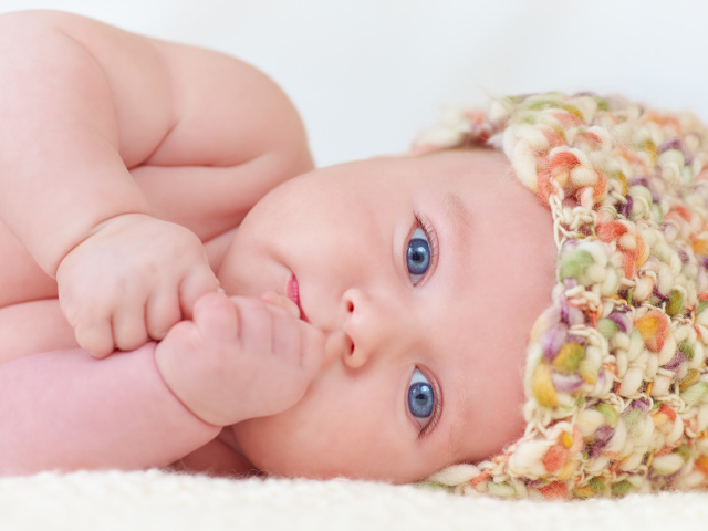 Голубоглазый грудной ребенок в шапке 