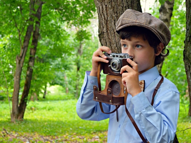 Мальчик с фотоаппаратом в руках в парке