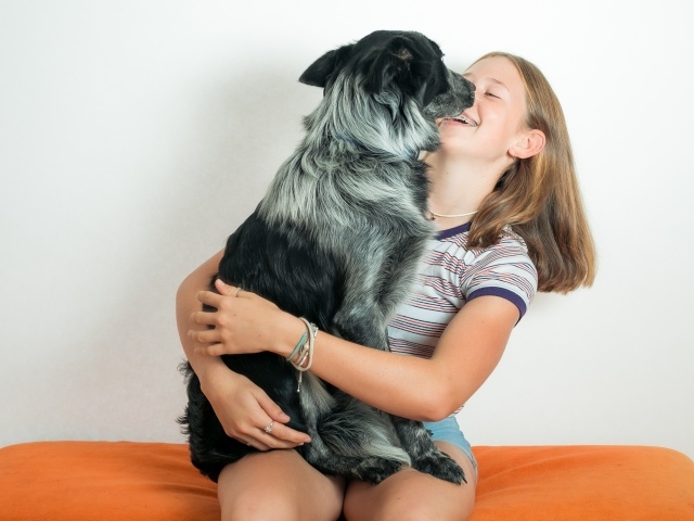 Веселая девочка с собакой в руках 