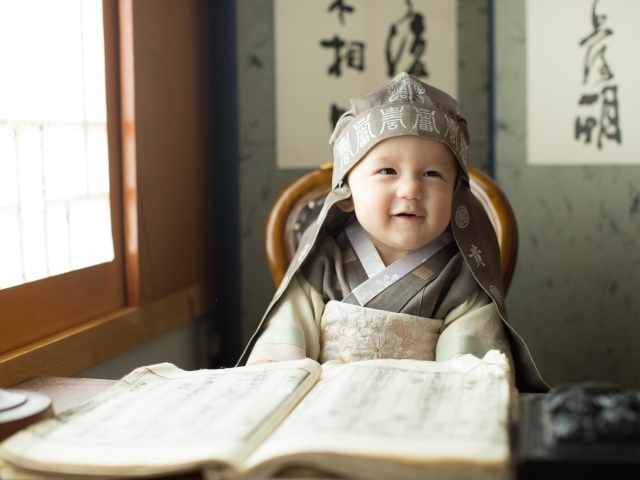 Маленький азиатский мальчик за столом с книгой