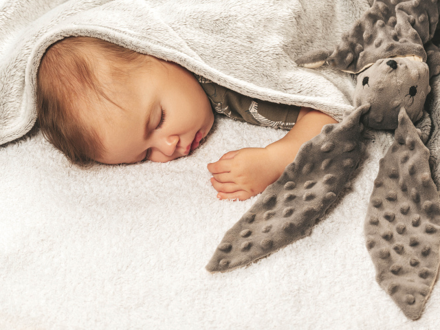 Маленький ребенок спит с игрушкой под одеялом