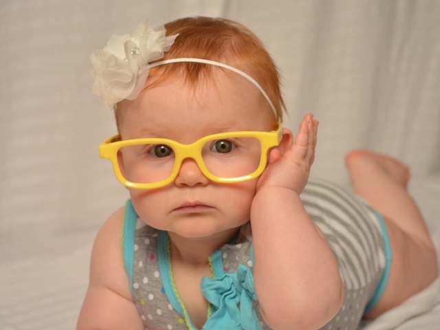Маленькая красивая девочка в очках с обручем на голове