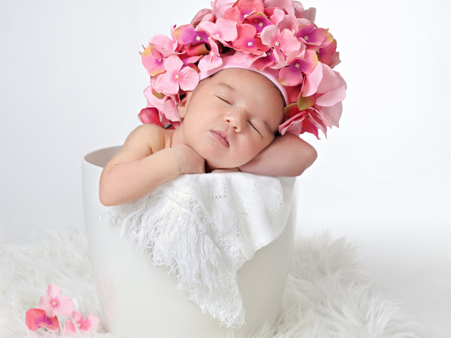 Маленький ребенок в шапке с цветами в горшке 