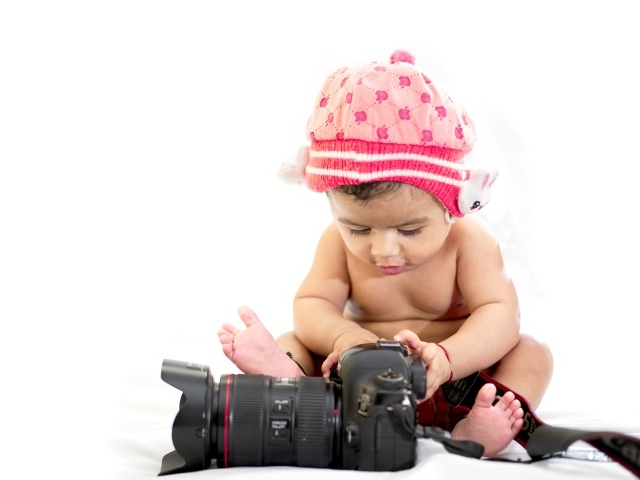 Маленький ребенок с фотоаппаратом на белом фоне 