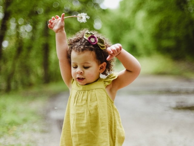 Маленькая девочка в платье с одуванчиком в руке