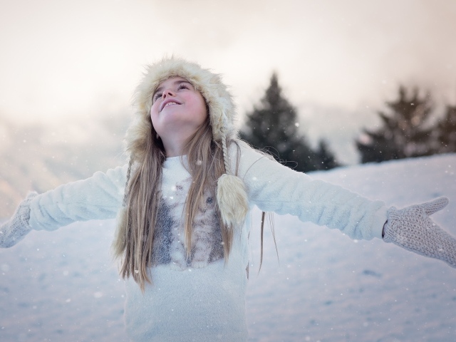 Маленькая девочка в теплой шапке на улице зимой
