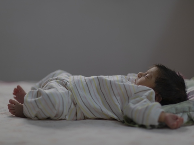 Маленький спящий грудной ребенок на кровати 