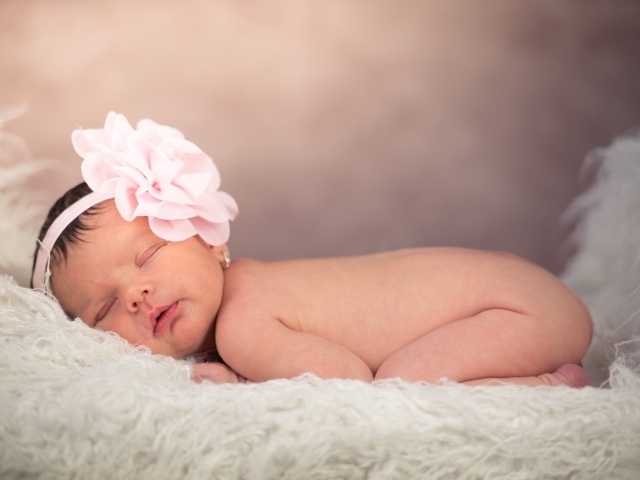 Новорожденная девочка с большим цветком на голове 