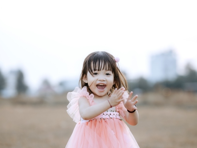 Довольная маленькая девочка в розовом платье 