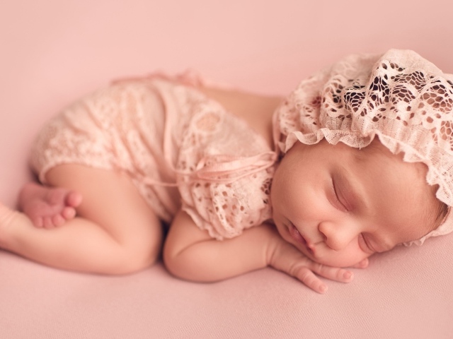 Спящий грудной ребенок в розовом костюме 