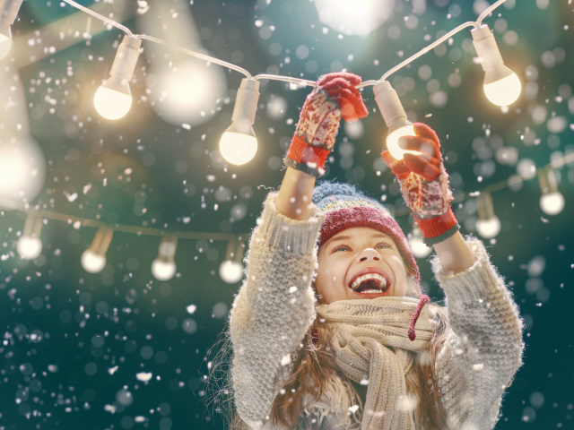 Улыбающаяся девочка вешает лампочки 