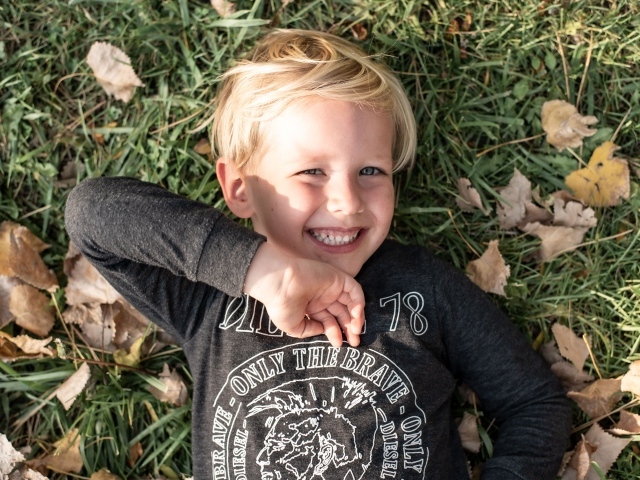 Улыбающийся маленький мальчик лежит на траве