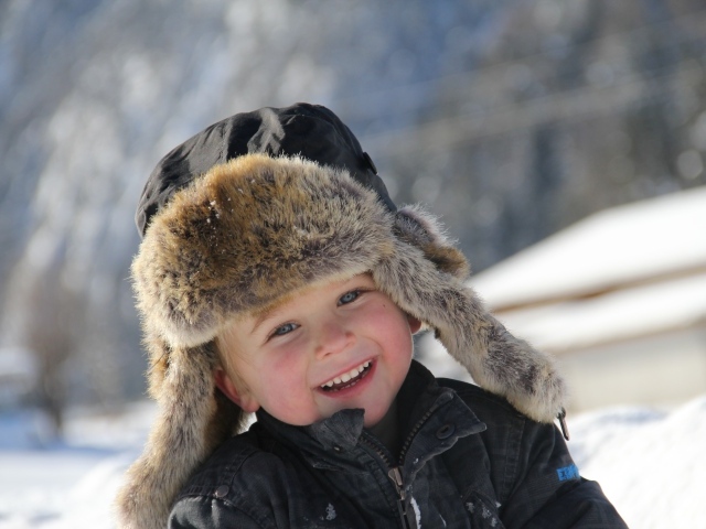 Улыбающийся  маленький мальчик в зимней шапке 