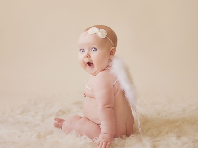 Удивленный грудной ребенок с белыми крыльями за спиной 