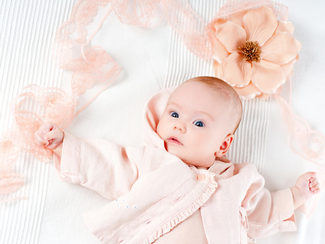 Удивленный новорожденный ребенок с цветком