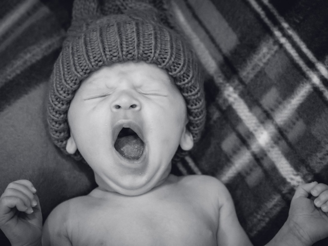 Зевающий ребенок в теплой шапке 