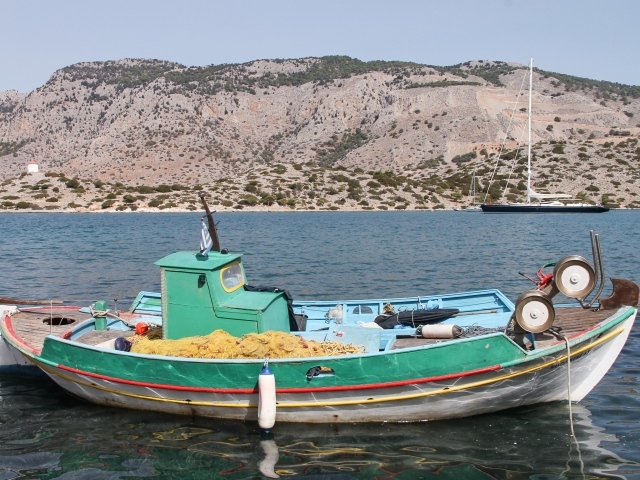 Рыбацкая лодка в воде на фоне горы