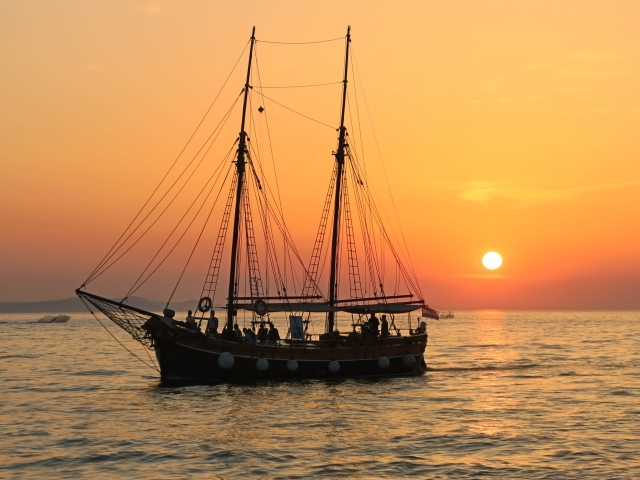 Большой корабль с опущенными парусами на закате солнца 