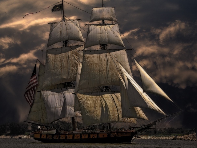 Больше судно с белыми парусами на фоне неба в сумерках 